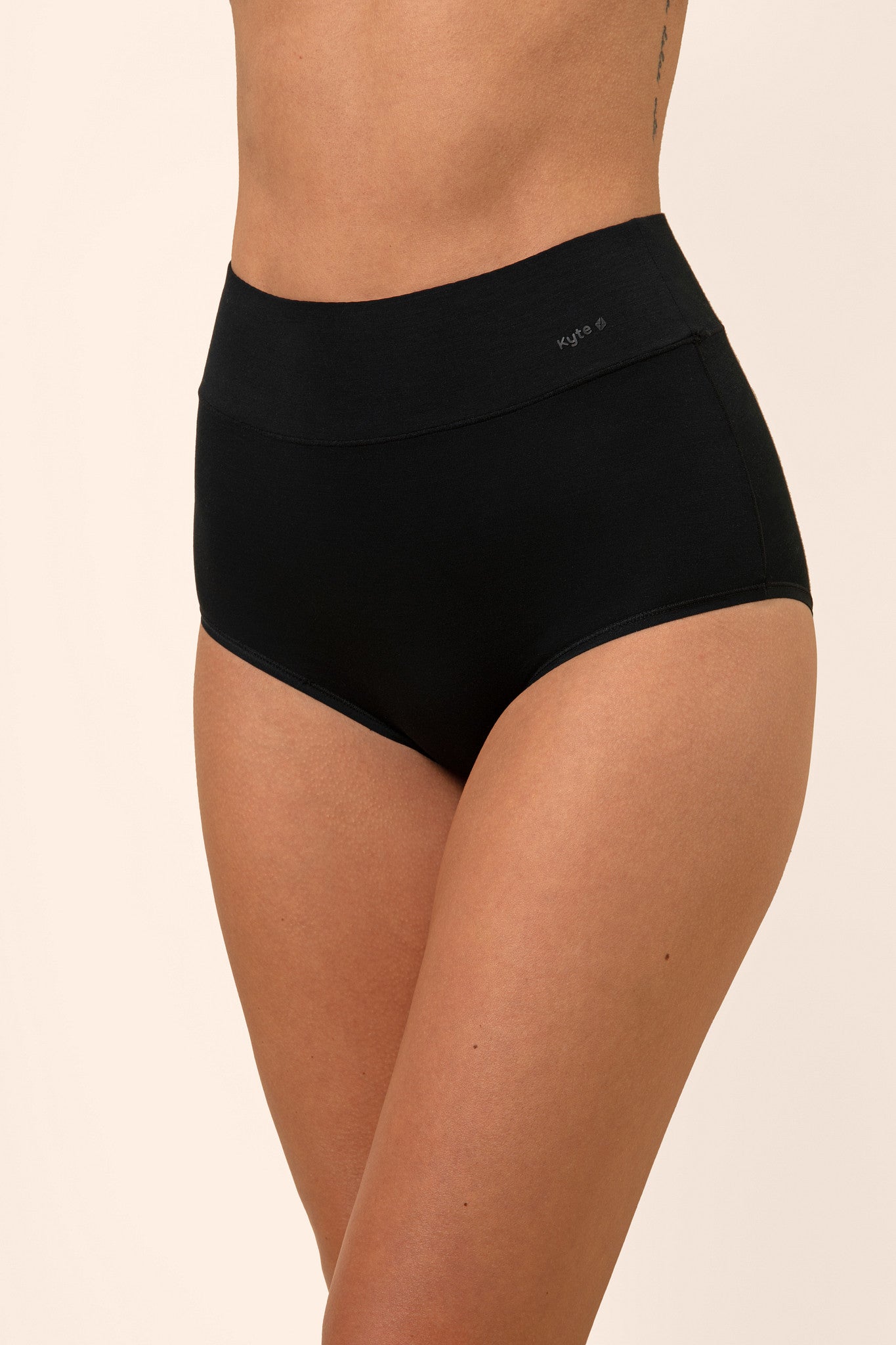 Black high-waisted bamboo underwear worn by a person on a beige background