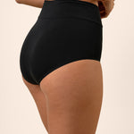 Black high-waisted bamboo underwear worn by a person on a beige background showing side coverage