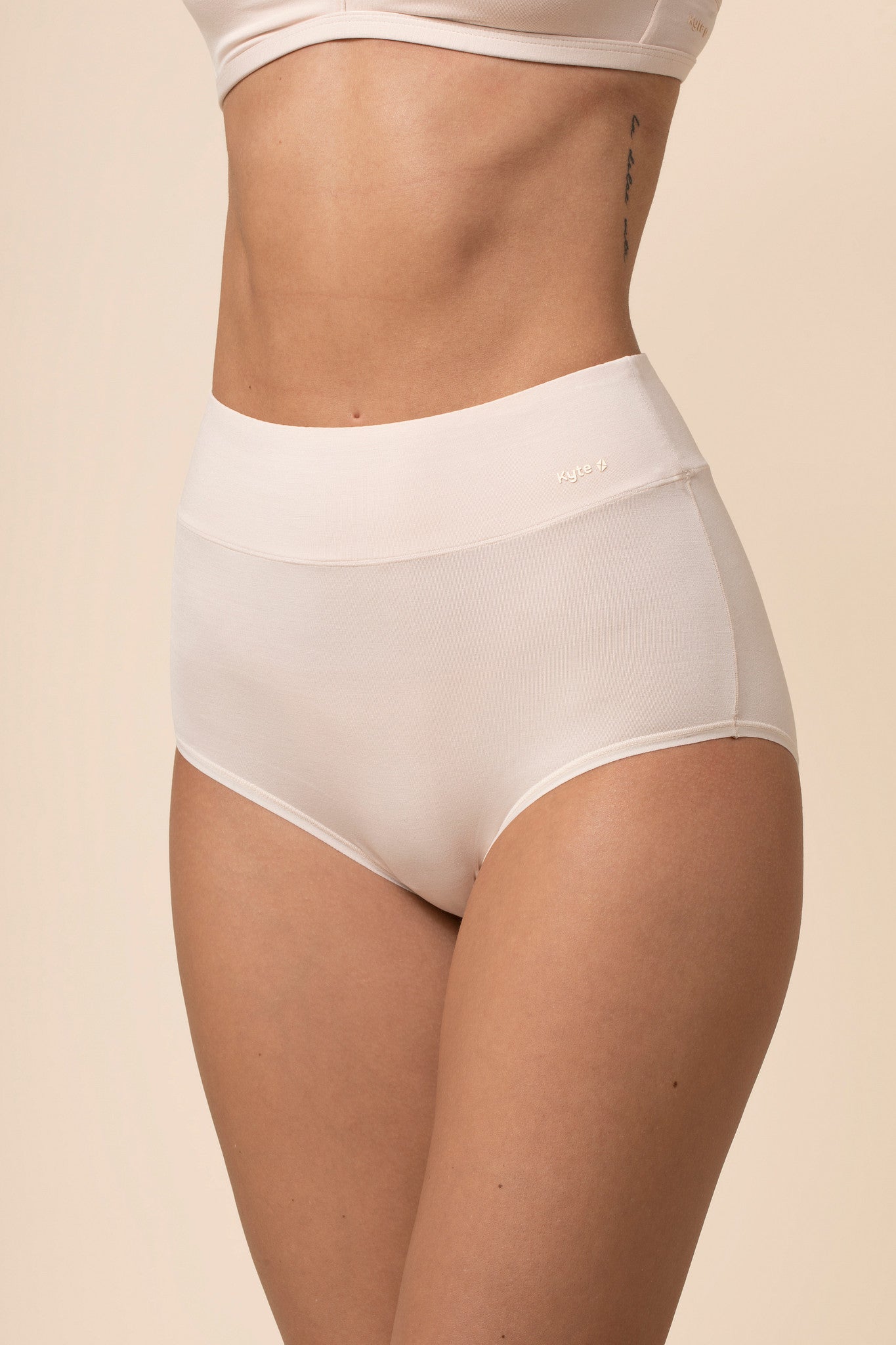 Cream high-waisted underwear worn by a person on a beige background