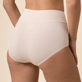Person wearing cream high-waisted underwear on a beige background