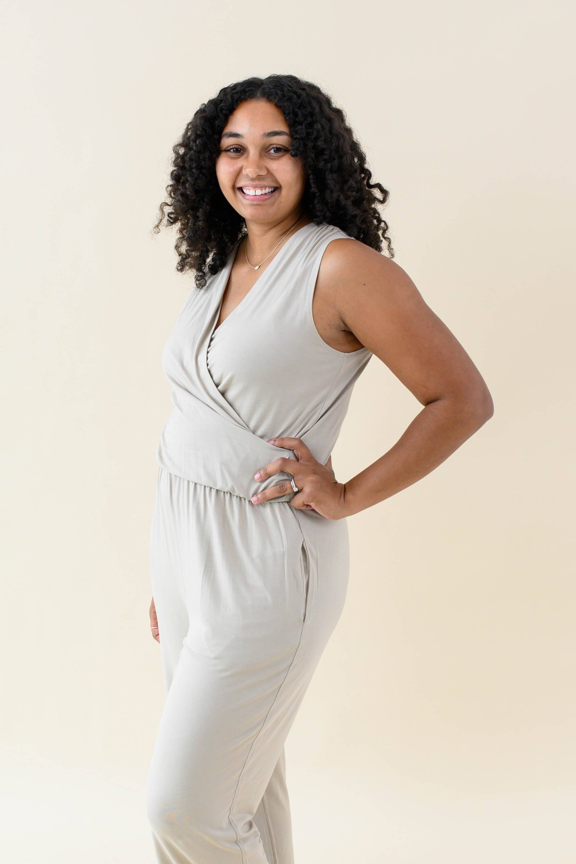 Smiling model wearing the Women's Jumpsuit in Almond with one hand on hip