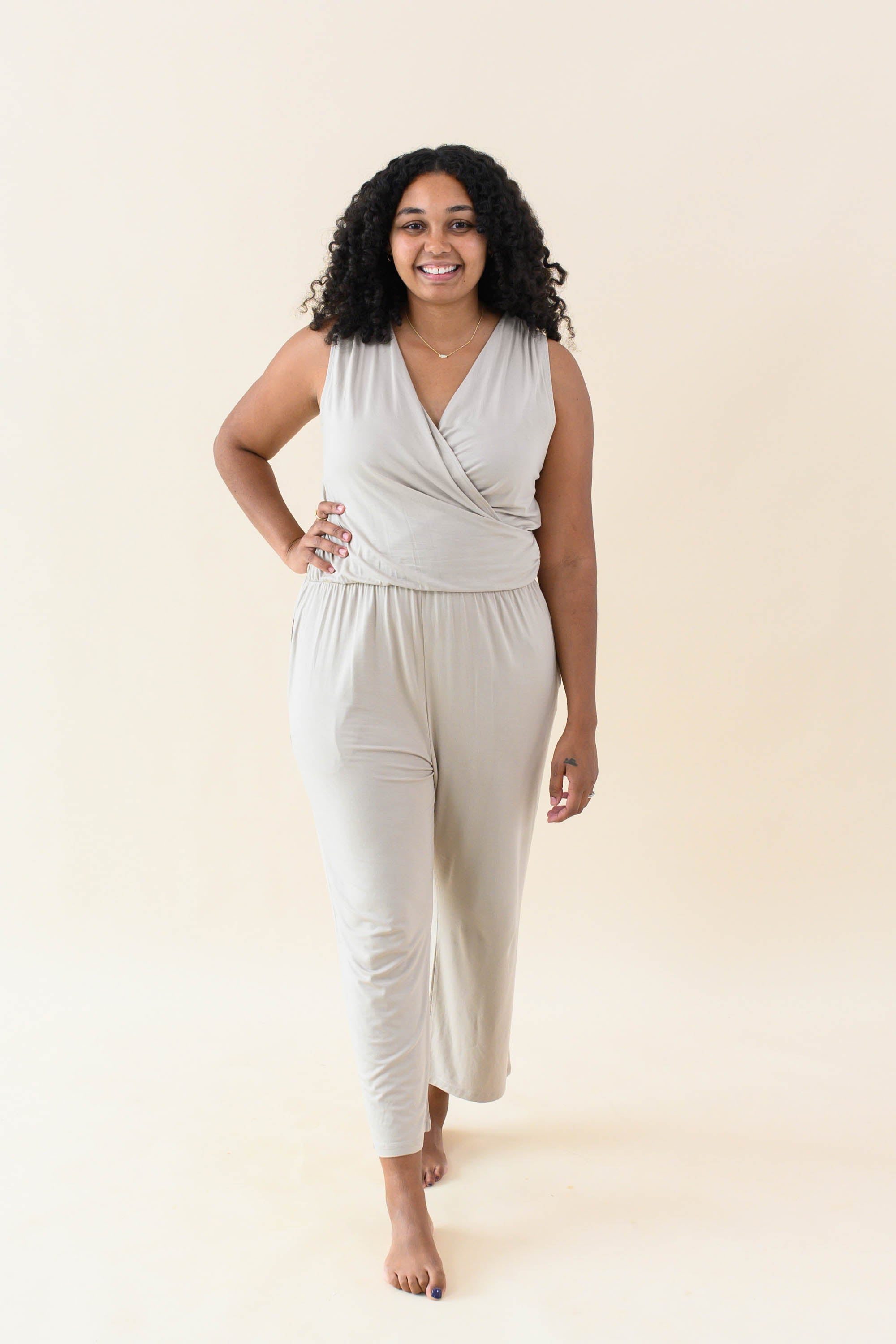 Model walking in the Women's Jumpsuit in Almond with one hand on hip