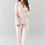 Smiling model wearing Kyte Baby's Women's Long Sleeve Pajama Set in Blush with Cloud Trim