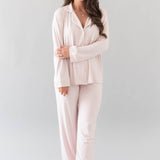 Smiling model wearing Kyte Baby's Women's Long Sleeve Pajama Set in Blush with Cloud Trim