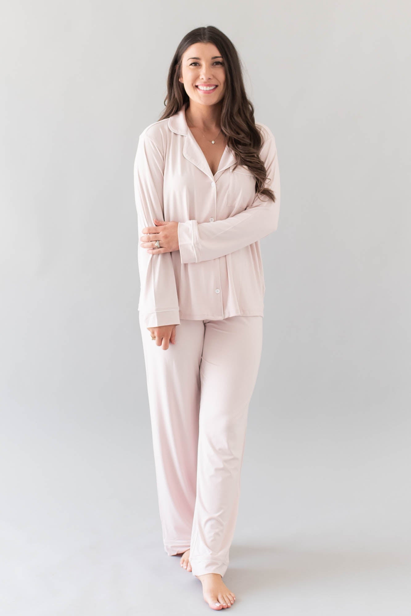 Smiling model wearing Kyte Baby's Women's Long Sleeve Pajama Set in Blush with Cloud Trim