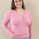 Female wearing Women's Long Sleeve Henley Tee in Apple Blossom with light wash jeans