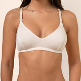 Woman wearing a light beige nursing bra and underwear set against a beige background