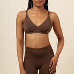 Woman wearing a brown bra and shorts set on a beige background