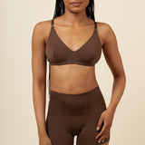 Woman wearing a brown bra and shorts set on a beige background