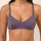 Woman wearing a purple nursing bra against a plain background