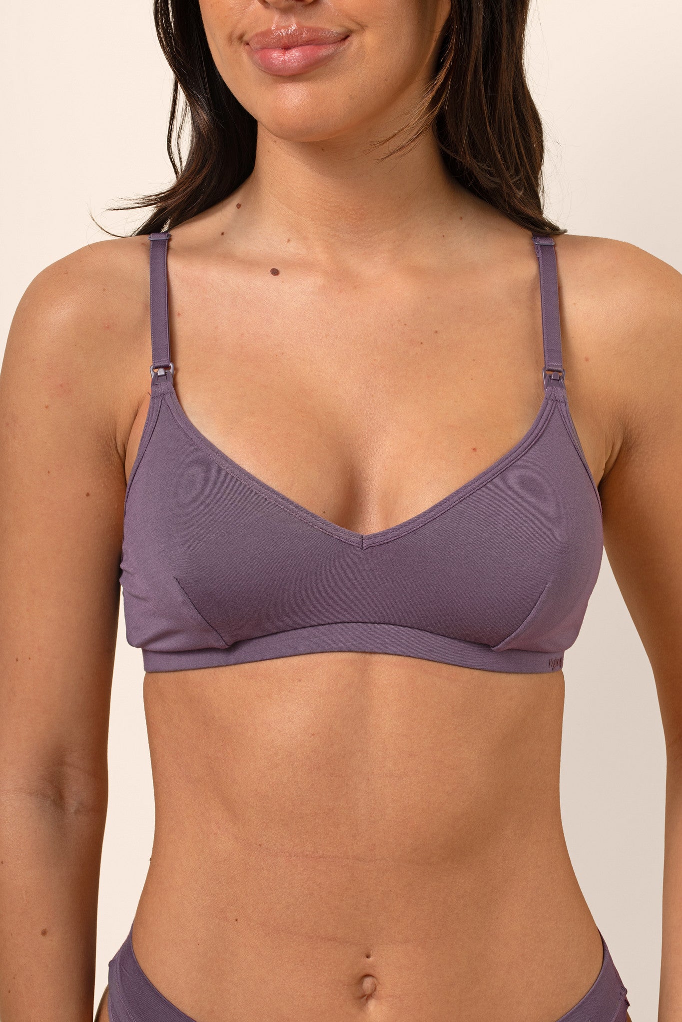 Woman wearing a purple nursing bra against a plain background