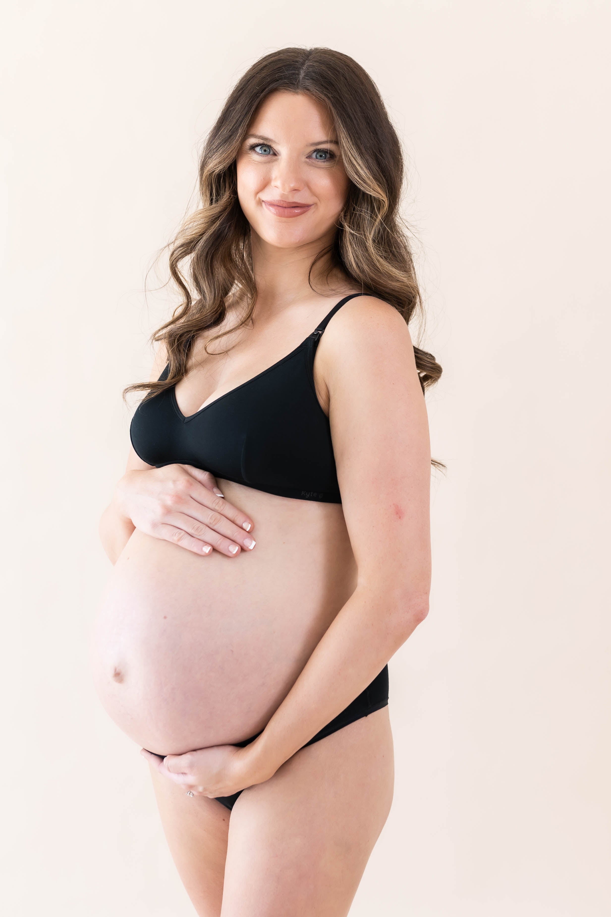Expectant mother cradling her baby bump wearing the Women's Nursing Bra in Midnight
