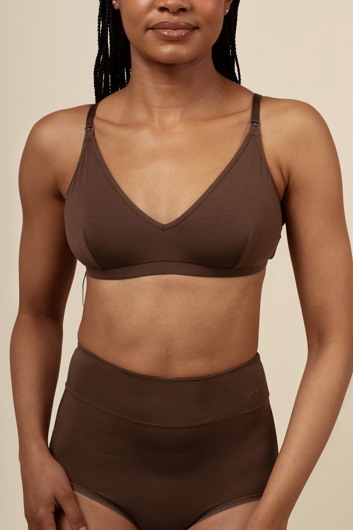 Woman wearing a brown nursing bra and high-waisted leggings against a beige background