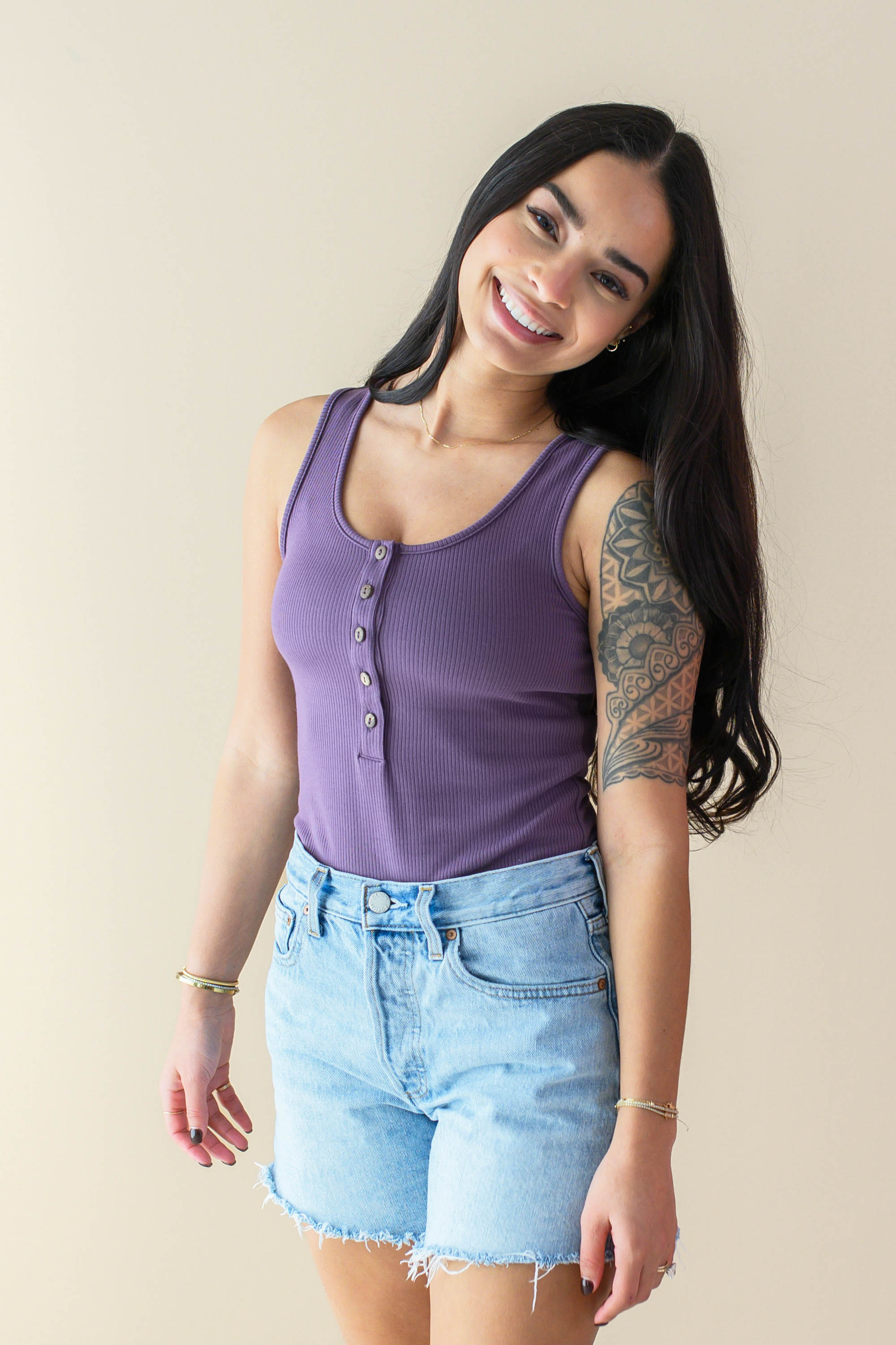 Female model wearing the Women’s Ribbed Henley Bodysuit in Currant paired with Jean Shorts