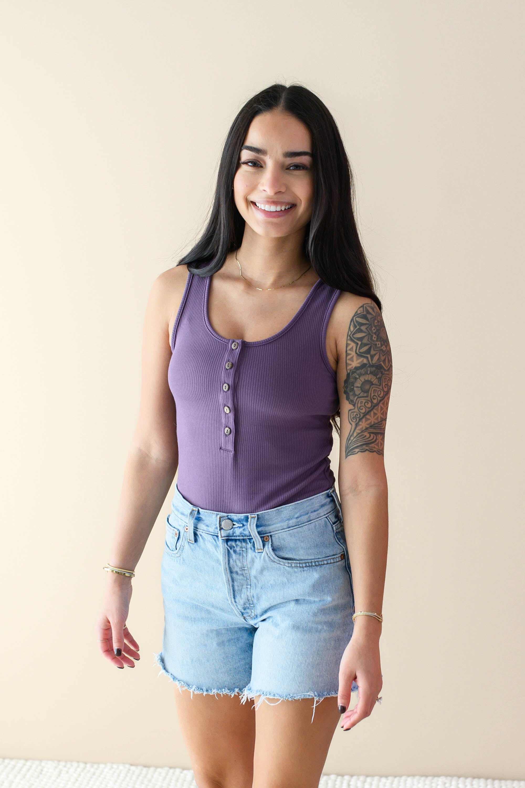 Smiling model wearing the Women’s Ribbed Henley Bodysuit in Currant