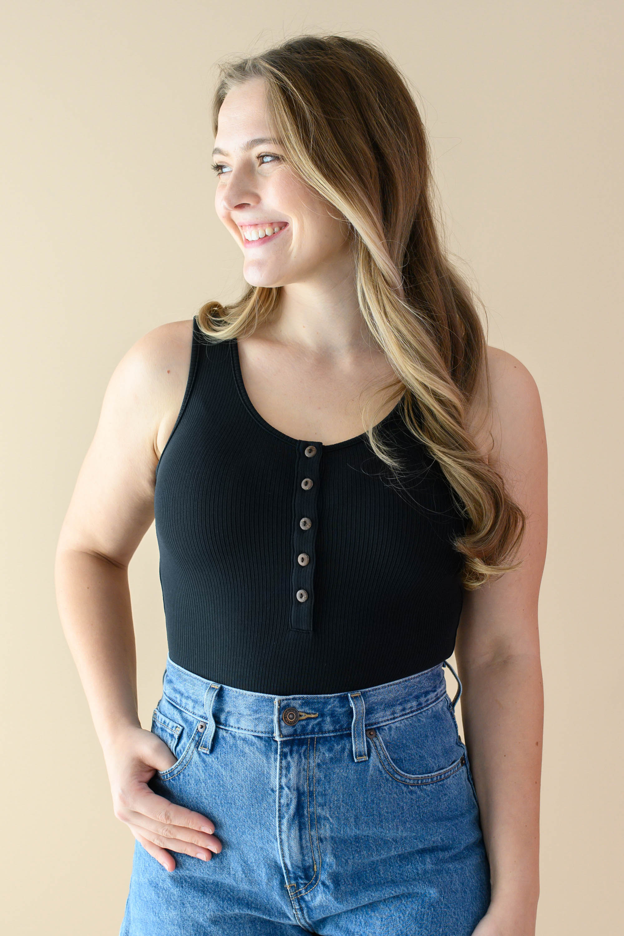 Smiling female wearing the Women’s Ribbed Henley Bodysuit in Midnight