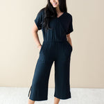 Smiling model wearing the Women's Ribbed Jumpsuit in Midnight with both hands in pockets