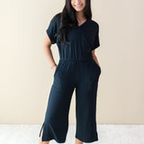 Female model wearing the Women's Ribbed Jumpsuit in Midnight with both hands in pockets