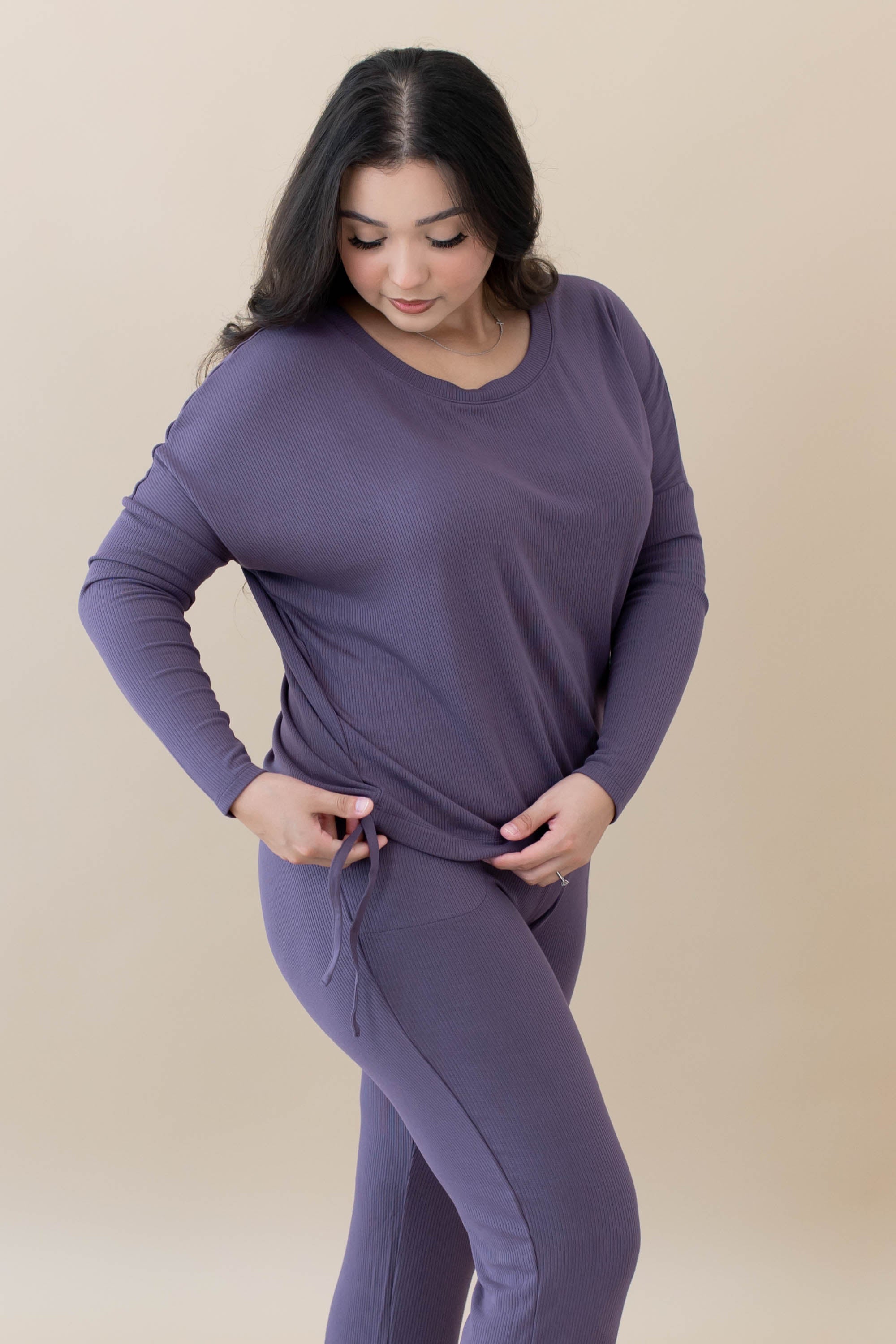 Female showing the drawstring feature on the bottom of the shirt for cinching for the Women's Ribbed Long Sleeve Drop Shoulder Top in Currant