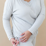 Model showing the drawstring feature for cinching on the bottom of the Women's Ribbed Long Sleeve Drop Shoulder Top in Oat