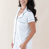 Female model wearing Kyte Baby's Women's Short Sleeve Pajama Set in Snow with Midnight Trim
