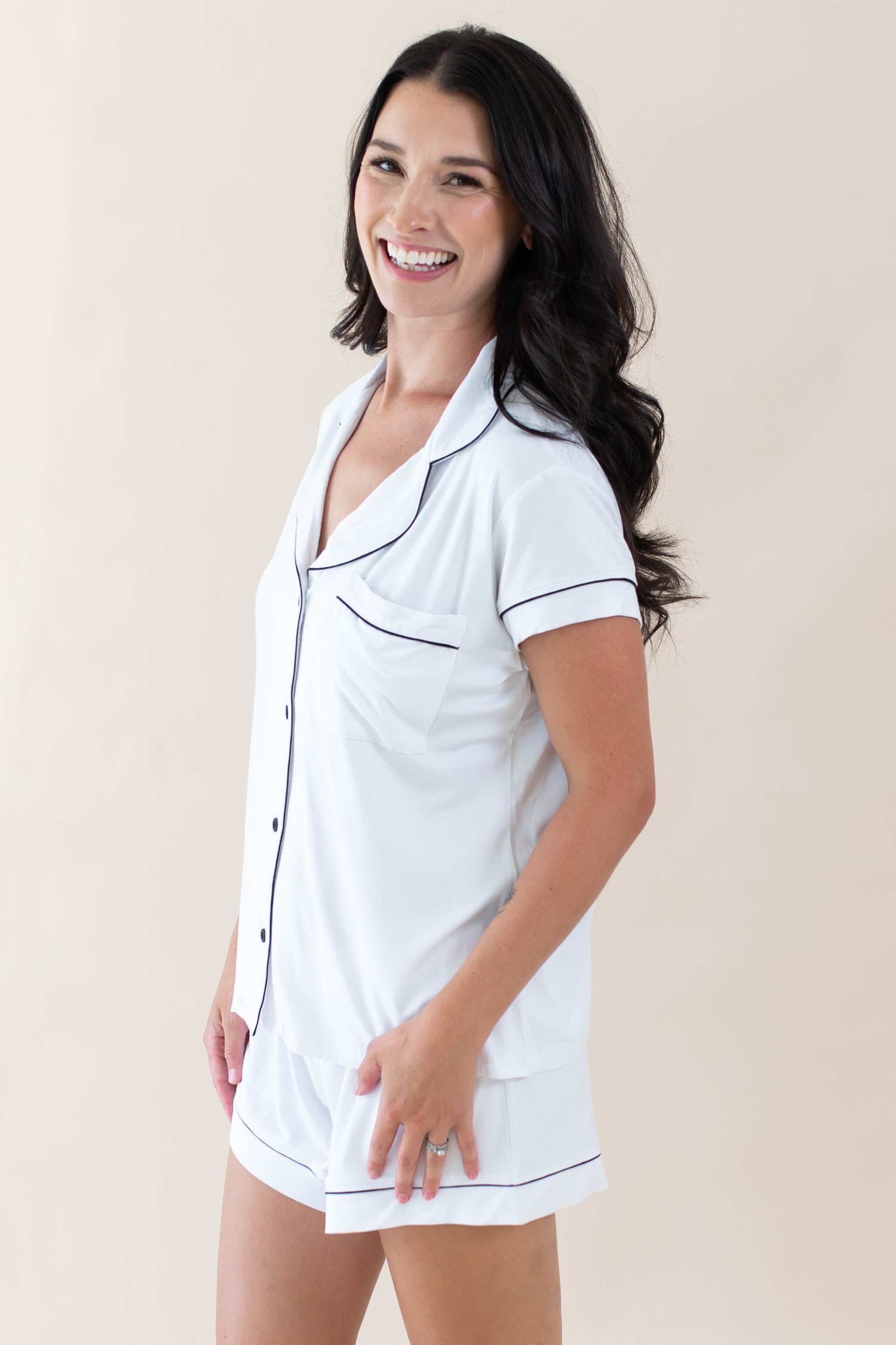 Female model wearing Kyte Baby's Women's Short Sleeve Pajama Set in Snow with Midnight Trim