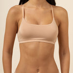 Woman wearing a beige bra and underwear set against a neutral background