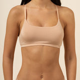 Woman wearing a beige bra and underwear set against a neutral background