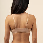 Woman wearing a beige bra and underwear set against a beige background