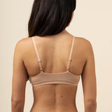 Woman wearing a beige bra and underwear set against a beige background
