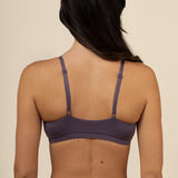Woman wearing a purple bra and leggings on a beige background