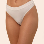 Light cream colored thong worn by a person on a beige background