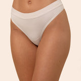 Light cream colored thong worn by a person on a beige background