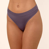 Purple thong worn by a person on a beige background