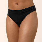 Black thong worn by a person on a beige background