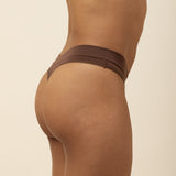 Brown thong underwear worn by a person on a beige background