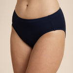 Person wearing a navy mid-waisted bikini bottom on a beige background