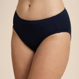 Person wearing a navy mid-waisted bikini bottom on a beige background
