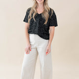 Model wearing the Women's Relaxed Fit V-Neck in Midnight Leopard paired with white jeans