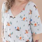 Woman wearing a light blue t-shirt with cartoon Winnie the Pooh character print against a beige background