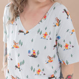Woman wearing a light blue t-shirt with cartoon Winnie the Pooh character print against a beige background
