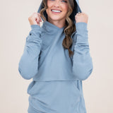 Smiling model wearing the Women's French Terry Nursing Hoodie in Slate with the hoodie up and her hands on the hood