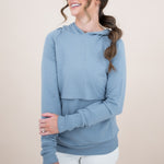 Smiling female model wearing the Kyte Women's French Terry Nursing Hoodie in Slate with one hand across her stomach 