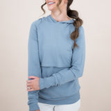 Smiling female model wearing the Kyte Women's French Terry Nursing Hoodie in Slate with one hand across her stomach 
