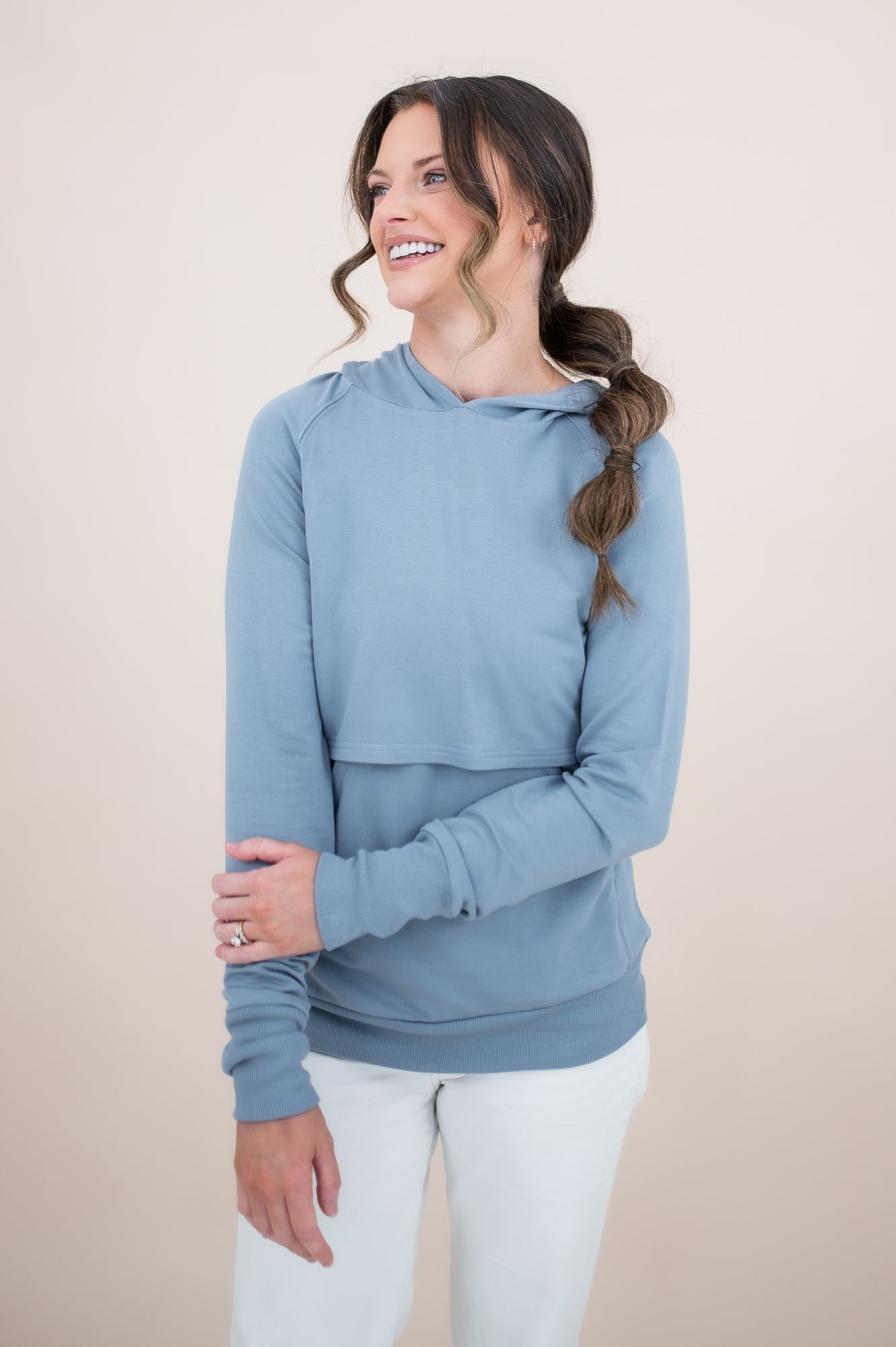 Smiling female model wearing the Kyte Women's French Terry Nursing Hoodie in Slate with one hand across her stomach 