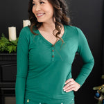 Model looking to the side with her hand on her hip while wearing the Women's Long Sleeve Henley Tee in Emerald