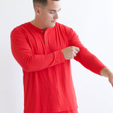 Male model readjusting sleeve while wearing the Men's Long Sleeve Henley Top in Cardinal