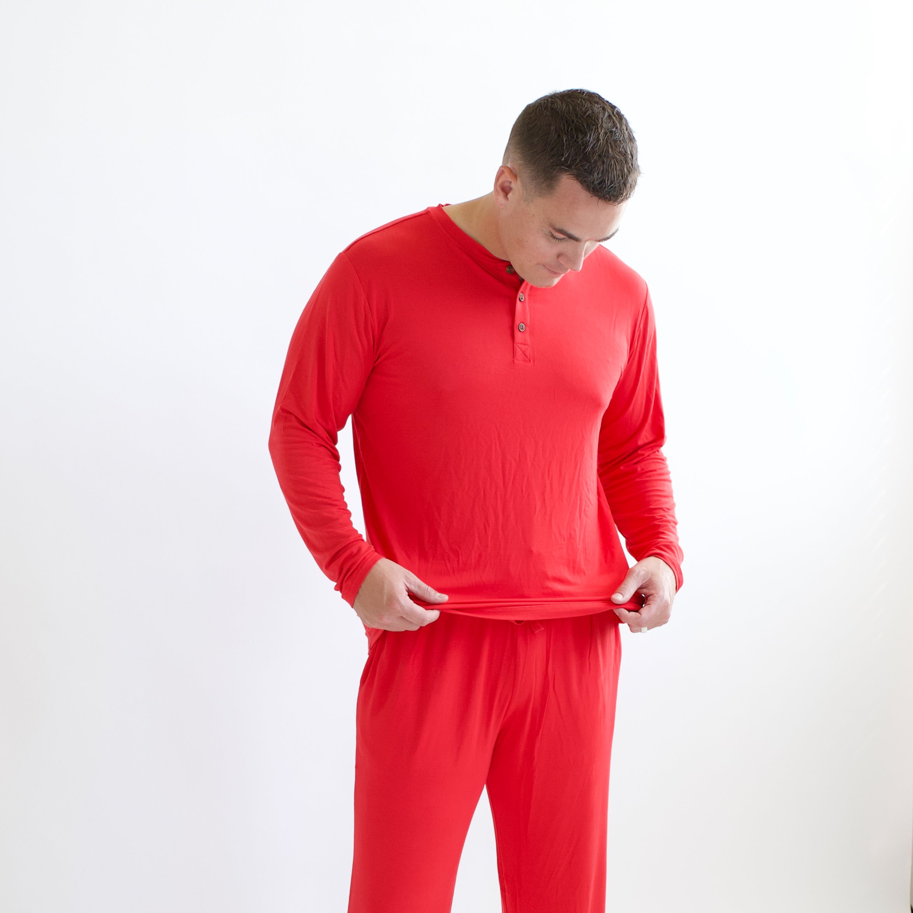 Man adjusting bottom of Men's Long Sleeve Henley Top in Cardinal