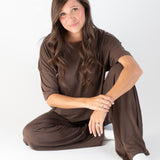 Model sitting while wearing the Women's Wide Leg Pant in Espresso paired with the matching tee