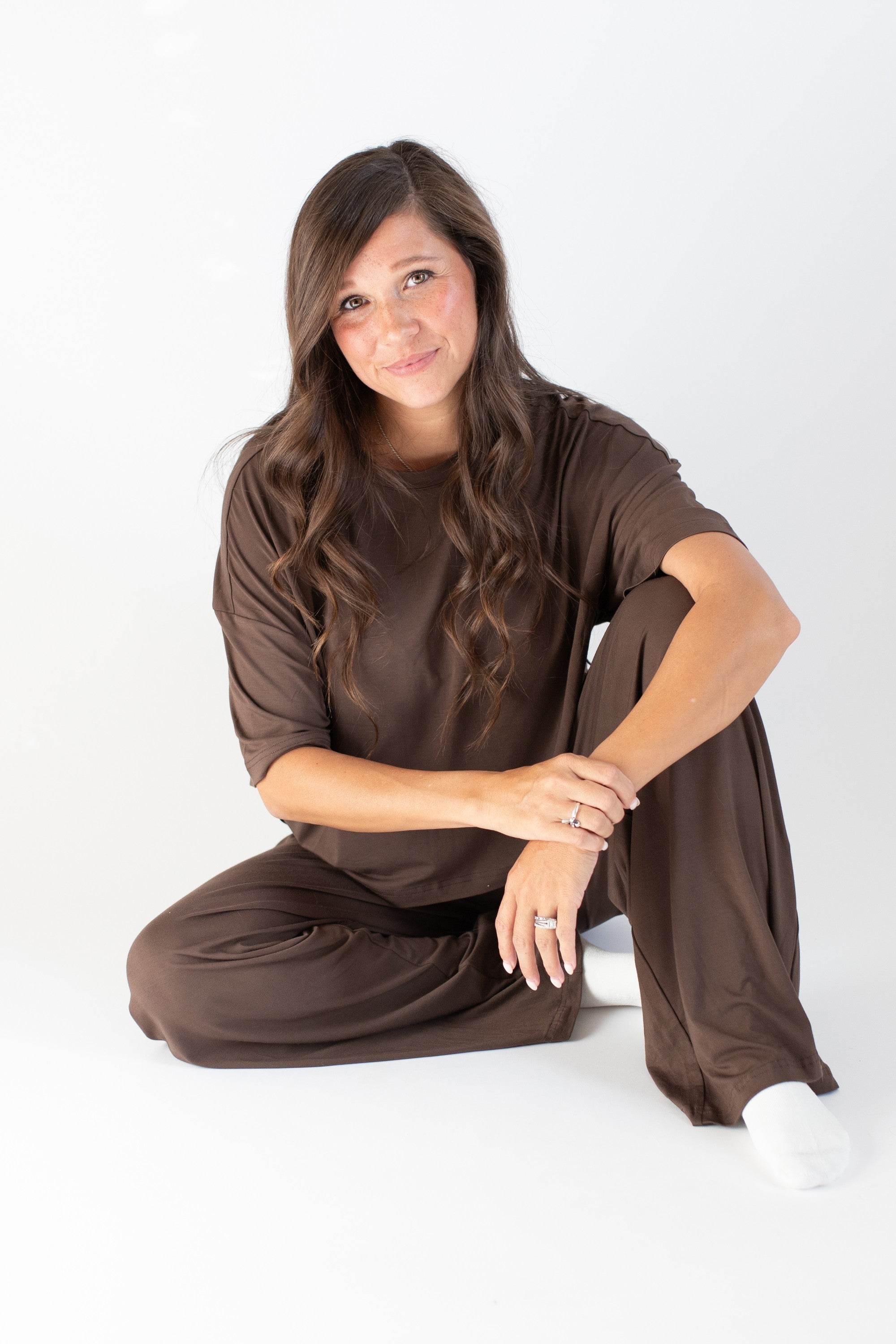 Model sitting while wearing the Women's Wide Leg Pant in Espresso paired with the matching tee